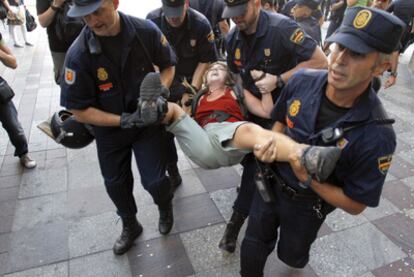 Cuatro agentes trasladan a una chica durante el desalojo de la Puerta del Sol.