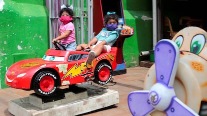 Dos niñas juegan en un coche llevando mascarilla, en Nicaragua.