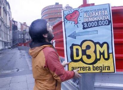 Un hombre coloca el pasado 13 de enero en Bilbao un cartel que pide firmas de apoyo para D3M.