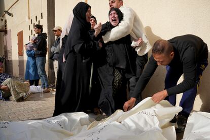 Una mujer llora junto a los cadáveres de varios familiares muertos durante los bombardeos israelíes, en la morgue del hospital de Deir Al balah, este domingo.