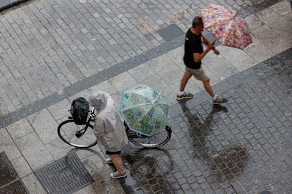 Dos personas caminan bajo la lluvia en una calle de València este sábado.