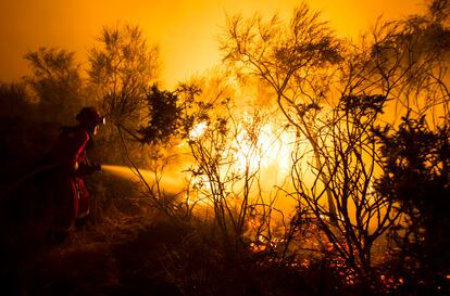 El incendio forestal que afecta a la parroquia de Lucenza, en el municipio ourensano de Cualedro, continúa activo y ha afectado ya a 2.000 hectáreas de terreno, según las últimas estimaciones de la Consellería do Medio Rural. En la imagen, trabajos de extinción durante la madrugada.