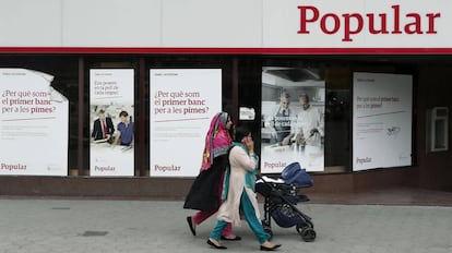 Unas mujeres pasan por delante de una oficina del Banco Popular, en Barcelona.