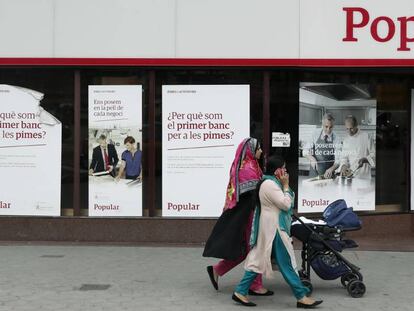 Unas mujeres pasan por delante de una oficina del Banco Popular, en Barcelona.