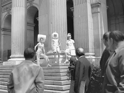 Lourdes Albert, a la derecha, y otras dos modelos posan con diseños de Antonio Nieto en la escalinata del madrileño palacio de la Bolsa en abril de 1967, mientras algunos curiosos se detienen a observar la escena.