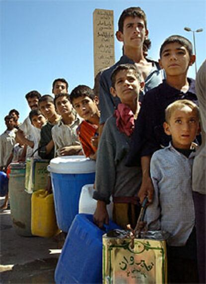 Niños iraquíes hacen cola para obtener agua potable ayer en Basora.