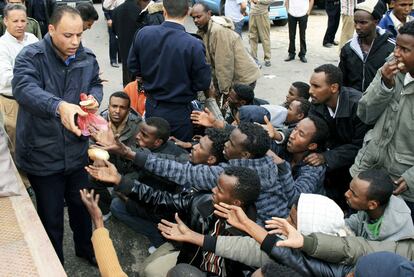 Un policía libio distribuye pan a inmigrantes en el puerto de Trípoli, en marzo pasado.