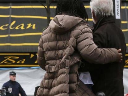 Dos personas se abrazan frente a la sala Bataclan, uno de los escenarios del atentado terrorista del viernes 13 de noviembre en Par&iacute;s.