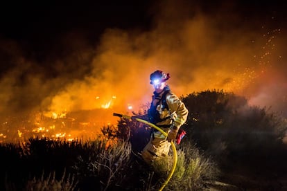 Los bomberos trabajan para extinguir el incendio de Thomas mientras se quema la carretera 101 hacia la autopista de la costa del Pacífico en Ventura, California.