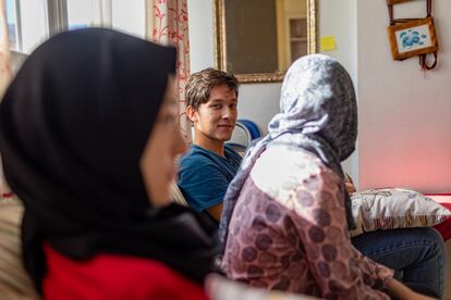El joven afgano Hujjat, junto a dos de sus hermanas, en el piso de acogida donde vive con toda su familia en España.