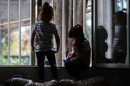 Dos niñas juegan junto a la ventana de su domicilio en Madrid.
