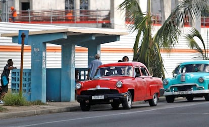 Dos automóviles clásicos pasan frente a una parada de autobus, el miércoles en La Habana (Cuba).