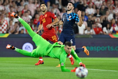 Marco Asensio observa como Dominik Livakovic, el portero de Croacia, despeja una pelota.