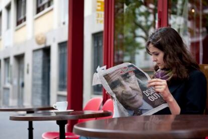 Una mujer lee el periódico 'Liberation' que muestra en portada la noticia sobre el arresto y detención del director del Fondo Monetario Internacional, Dominique Strauss Kahn, en una cafetería en París.