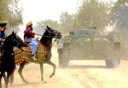 Combatientes a caballo de la Alianza del Norte pasan junto a un blindado en el frente de la provincia de Takhar, en el norte de Afganistán.