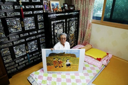 Kim Bok-dong, antigua "mujer de solaz" surcoreana, posa con una copia de su pintura titulada [i]El día que una niña de 14 años es raptada[/i] en su habitación del refugio La casa compartida para mujeres víctimas de los abusos sexuales de las tropas japonesas durante la Segunda Guerra Mundial. Durante una sesión de dibujo terapéutico con el que en la residencia intentan aliviar el trauma que ha quedado a estas mujeres, Kim realizó esta obra para describir lo que le ocurrió a ella. En 1940 fue secuestrada por tropas japoneses y usada como esclava sexual unas 15 veces al día entre semana y hasta 50 los sábados y domingos en varios burdeles militares en China, Hong Kong, Sumatra, Java, Malasia y SIngapur hasta que Japón se rindió.
