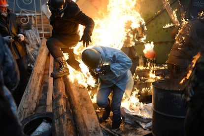 Los enfrentamientos entre los manifestantes opositores y las fuerzas antidisturbios se reanudaron en el centro de Kiev con gran violencia. En la imagen unos manifestantes se queman detrás de una de las barricadas en la plaza de la Independencia de Kiev, 20 de febrero de 2014.