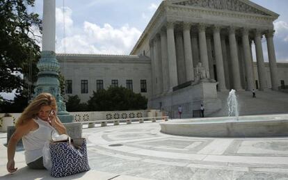 Una mujer usa su tel&eacute;fono m&oacute;vil delante del Tribunal Supremo. 