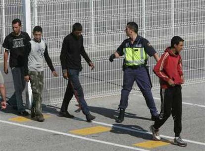 Un agente de la policía conduce a cuatro inmigrantes que intentaban entrar ilegalmente en España por el puerto de Algeciras, el pasado jueves.