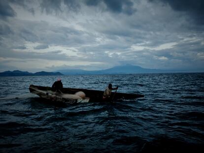 Nzibonera y Emanuel (derecha) reman en su canoa al atardecer mientras un fuerte viento empieza a soplar en el lago Kivu. La mayoría de los pescadores de las comunidades de Kivu del Sur son cristianos, pero algunos todavía hablan de los misteriosos poderes del lago, del que se rumorea que hace desaparecer barcos y tripulaciones durante la noche.