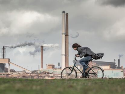 Una ciclista circula cerca de una fábrica de altos hornos en IJmuiden, Países Bajos.