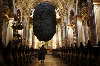 Una mujer camina bajo la obra "Para estar en el limbo" que cuelga del techo de la iglesia jesuita en Viena. La escultura, que mide ocho metros de altura y 700 kg de peso, fue creada por grupo de artistas Steinbrenner / Dempf y Huber como un homenaje a las piedras flotantes de René Magritte.