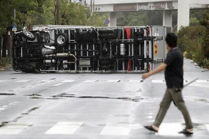 Un hombre mira un camión volcado después de un poderoso tifón en Osaka, oeste de Japón.