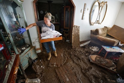 Sabra English señala la colección de curiosidades de su madre mientras saca documentos importantes de la casa de su padre, gravemente inundada.