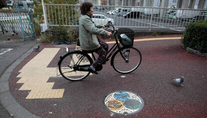 Una mujer pedalea junto a una alcantarilla decorada en Saitama.