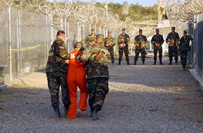 Dos guardias trasladan a un detenido en Guantánamo, en una imagen proporcionada por el Pentágono.