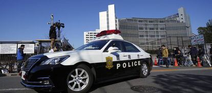 Un coche de polic&iacute;a, frente al edificio donde est&aacute; detenido Carlos Ghosn, donde hacen guardia grupos de periodistas. 