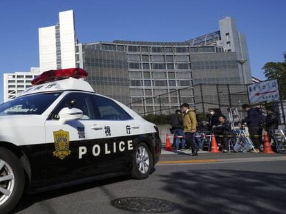 Un coche de polic&iacute;a, frente al edificio donde est&aacute; detenido Carlos Ghosn, donde hacen guardia grupos de periodistas. 