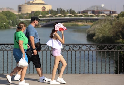 Una chica se protege del calor con un abanico mientras pasea este martes por el Puente de Triana, Sevilla.