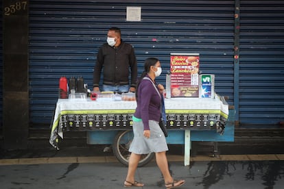 Una mujer camina frente a un vendedor ambulante, ambos con mascarilla de protección, este lunes, en Sao Paulo (Brasil).