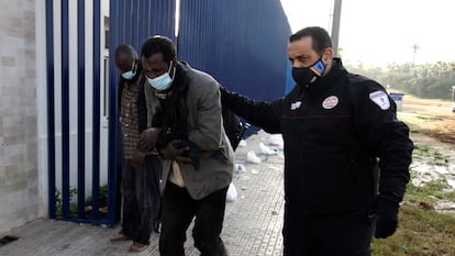 Dos de los migrantes que han participado en el salto acompañados por un vigilante de seguridad, este martes.