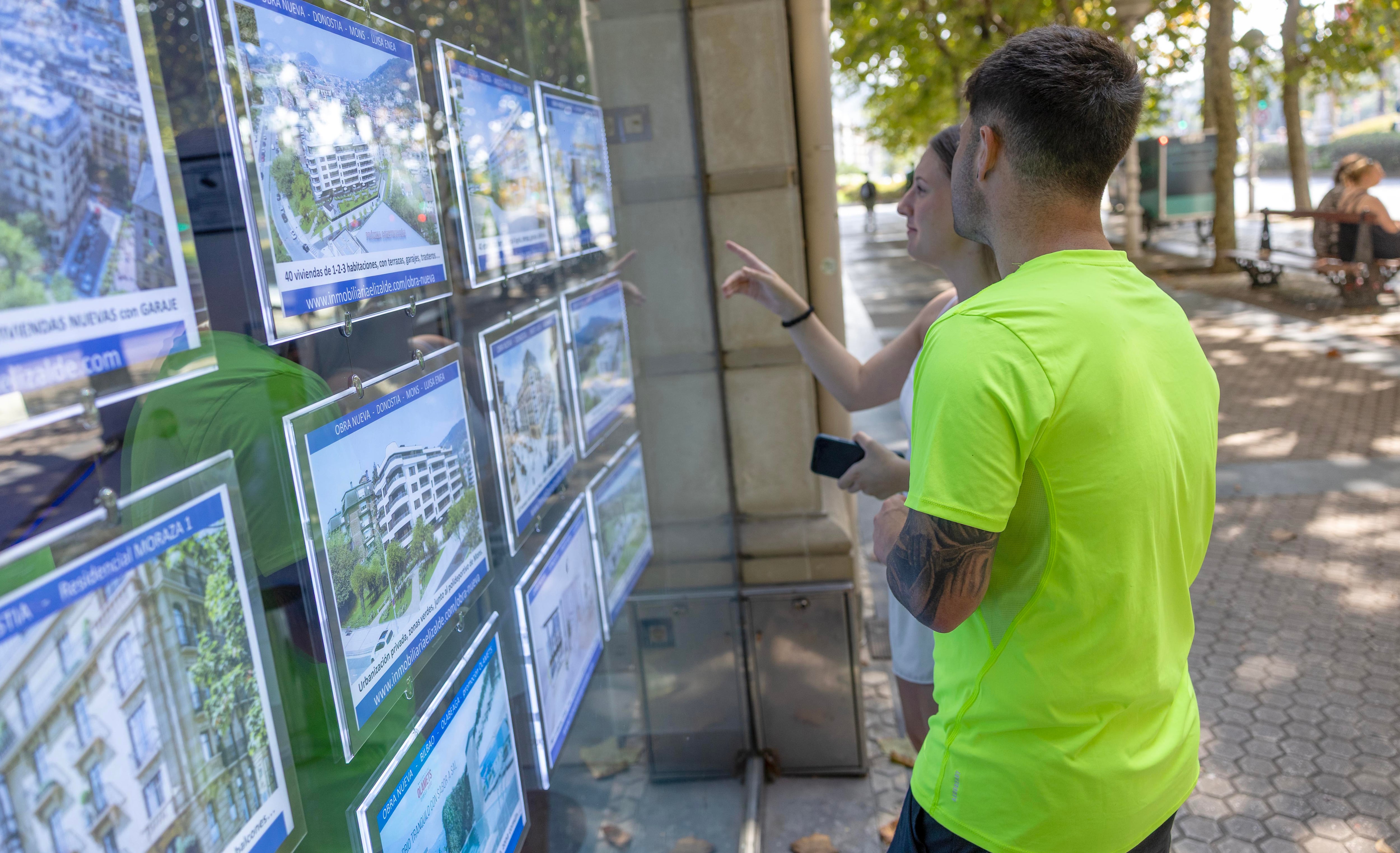 Dos jóvenes observan anuncios de pisos en una inmobiliaria del centro de San Sebastián.