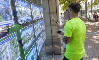 Dos jóvenes observan anuncios de pisos en una inmobiliaria del centro de San Sebastián.