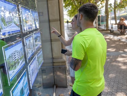 Dos jóvenes observan anuncios de pisos en una inmobiliaria del centro de San Sebastián.