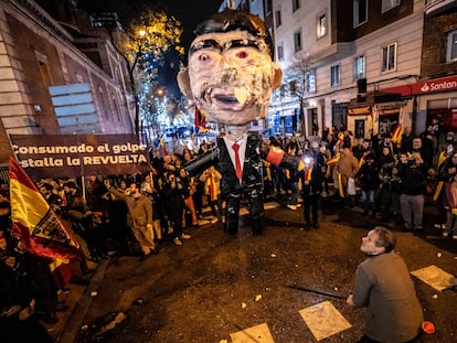 Un hombre se dispone a apalear un muñeco con la figura de Pedro Sánchez en la protesta cerca de la calle de Ferraz, en Madrid, en Nochevieja.