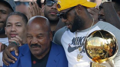 Former Cleveland Browns player Jim Brown, left, gets a hug from LeBron James, who holds the Larry O'Brien NBA championship trophy