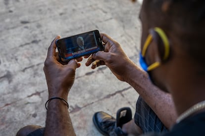 El haitiano Enold Desroches sigue en su celular la toma de posesión de Biden.