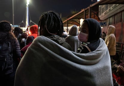 Dos migrantes cubiertos por una manta, durante la protesta en el cruce fronterizo. El grupo de centroamericanos y mexicanos pide que sus solicitudes de asilo a Estados Unidos sean atendidas.