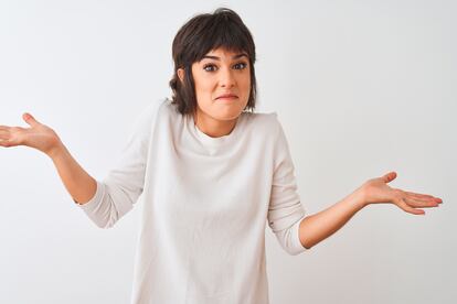 Young beautiful woman wearing casual t-shirt standing over isolated white background clueless and confused expression with arms and hands raised. Doubt concept.