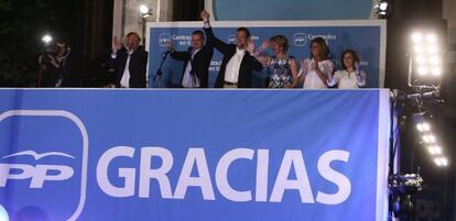 Rajoy y otros dirigentes del PP saludan a sus seguidores desde la sede de su partido en Madrid.