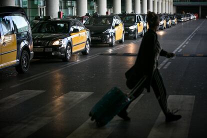 Una usuaria del aeropuerto de Barcelona cruza frente a los taxis de la T1.