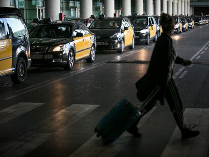Una usuaria del aeropuerto de Barcelona cruza frente a los taxis de la T1.