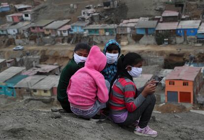 Niños con máscaras para prevenir la propagación del nuevo coronavirus, reciben clases virtuales a través de sus teléfonos móviles sentados en lo alto de una colina en el barrio de Puente Piedra, en las afueras de Lima, Perú.