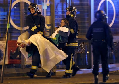 Dos bomberos trasladan a una mujer herida cerca de la sala Bataclan.