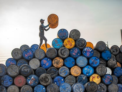 Un trabajador apila barriles de petróleo reciclados en la localidad india de Narayanganj.