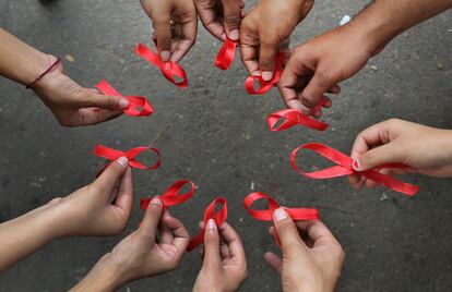 Un grupo de activistas de una ONG posan sosteniendo un lazo rojo en sus manos, el s&iacute;mbolo de la Lucha Contra el Sida. 